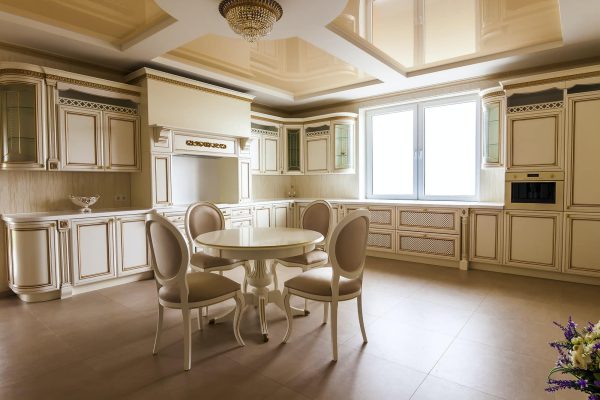 Luxury modern fitted kitchen interior. Kitchen in luxury home with beige cabinetry. Table and chairs